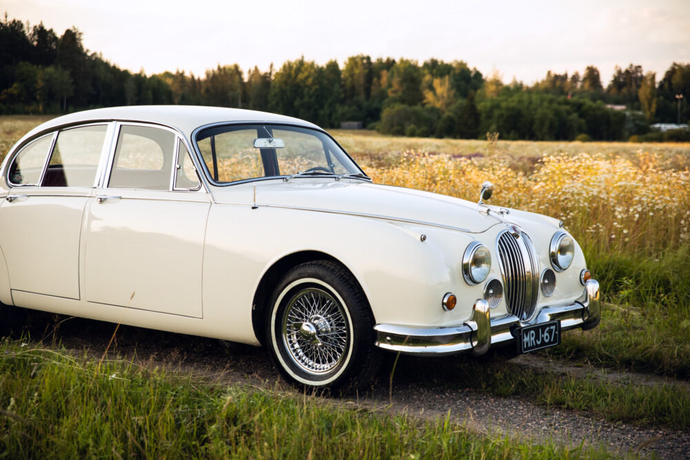 Vintage white Jaguar car parked in wildflower field