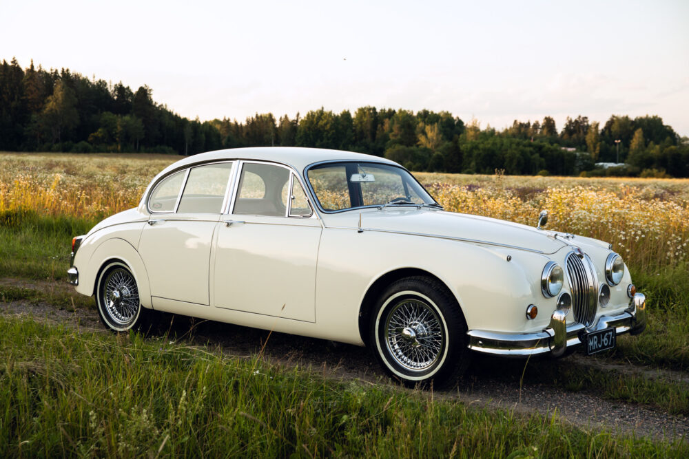 Vintage cream car parked in a scenic meadow at dusk