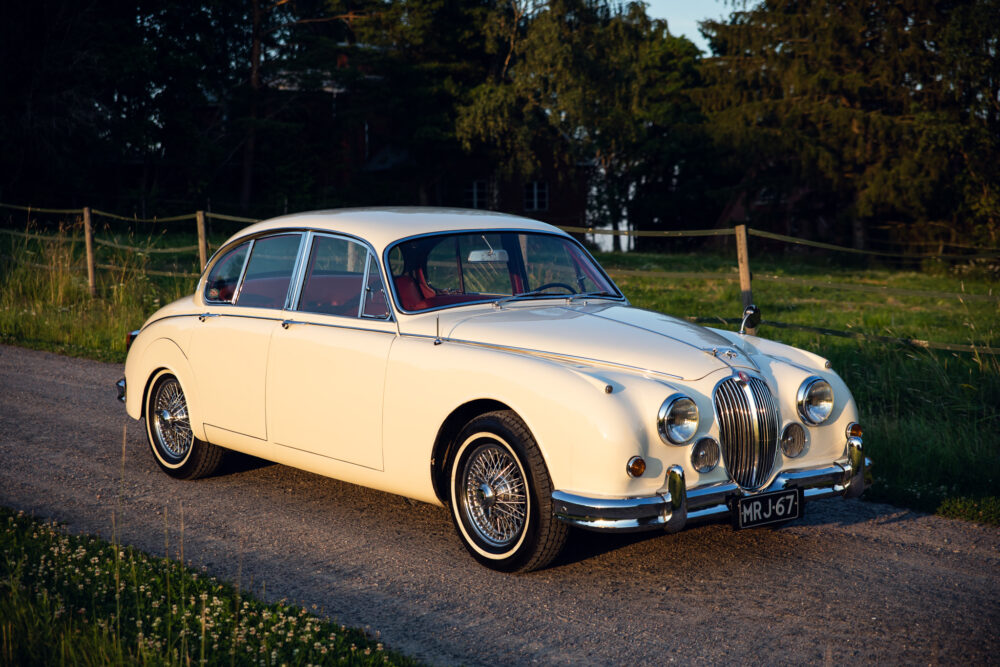 Vintage cream Jaguar sedan parked outdoors at dusk