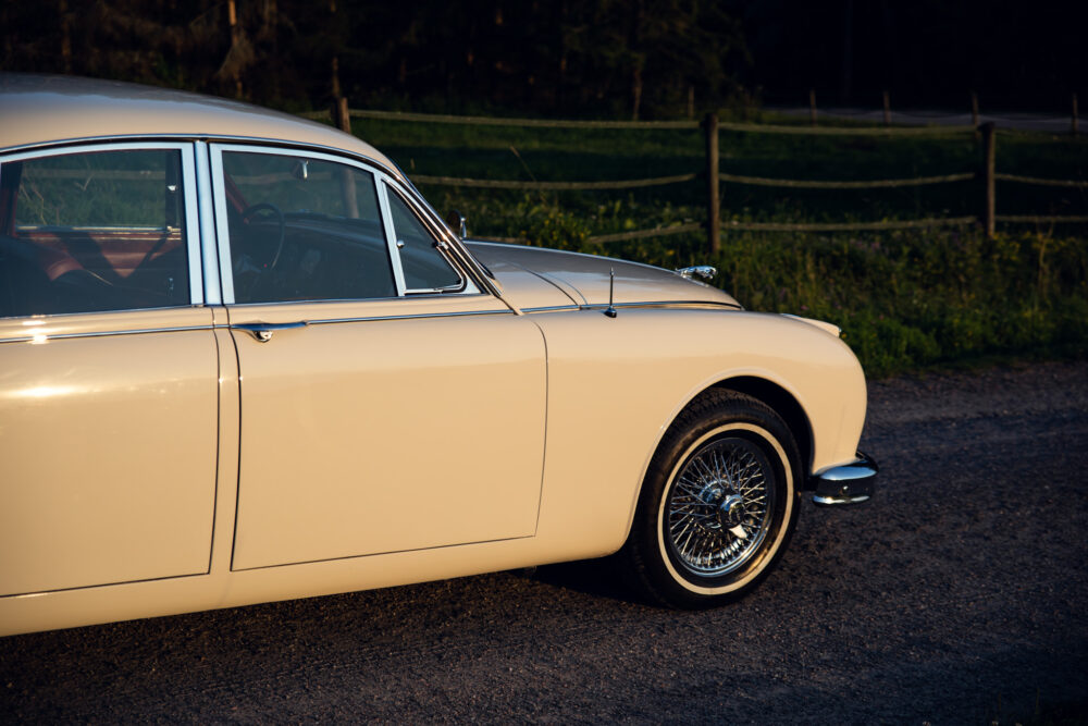 Vintage cream car with chrome spokes at sunset