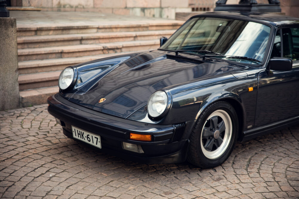 Vintage black Porsche car parked on cobblestone street