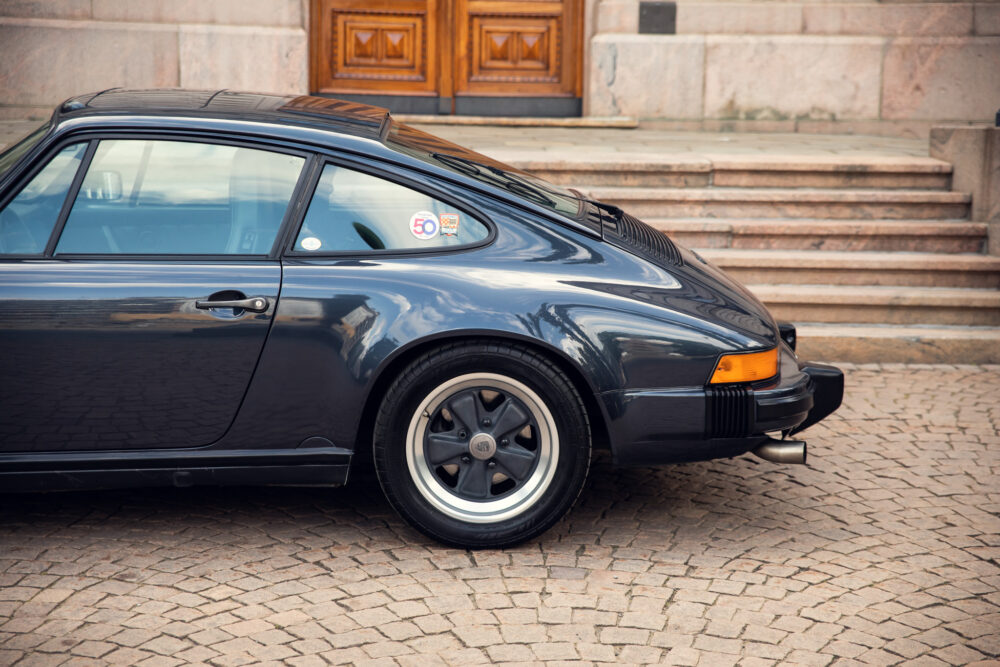 Vintage black Porsche parked near building stairs