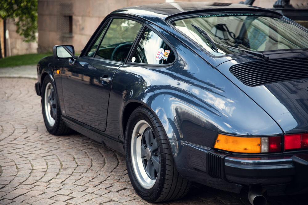 Classic black Porsche 911 on cobblestone driveway