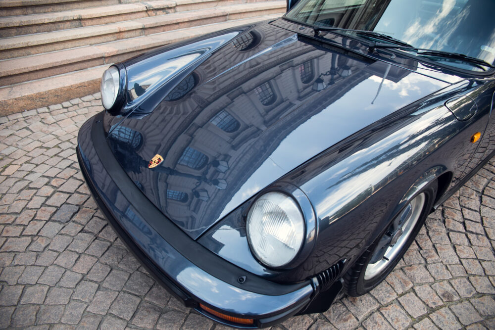 Classic black Porsche car on cobblestone street