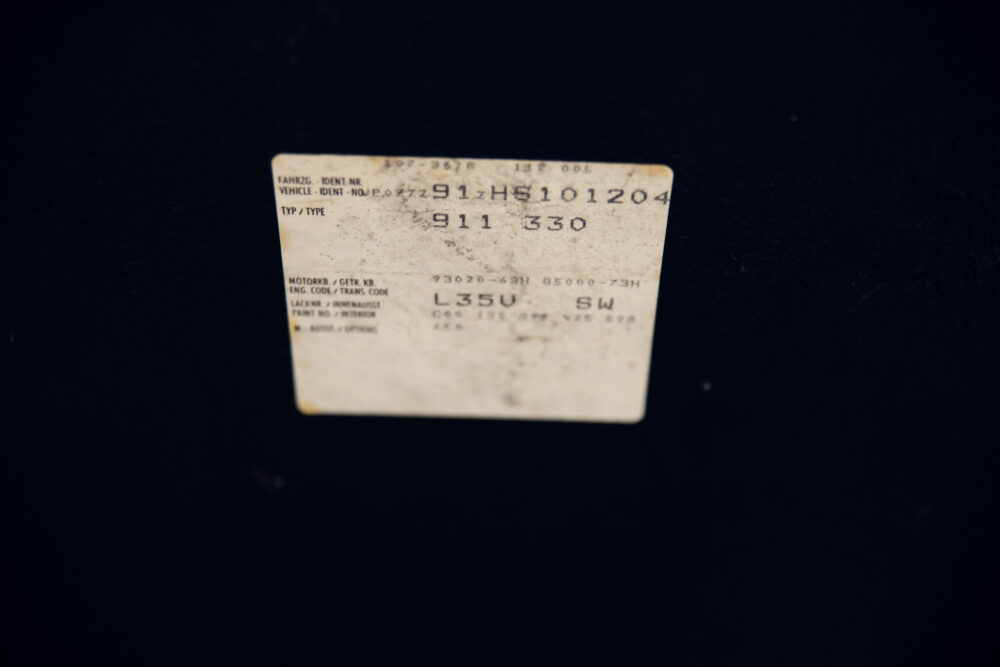 Old vehicle identification number label on black background