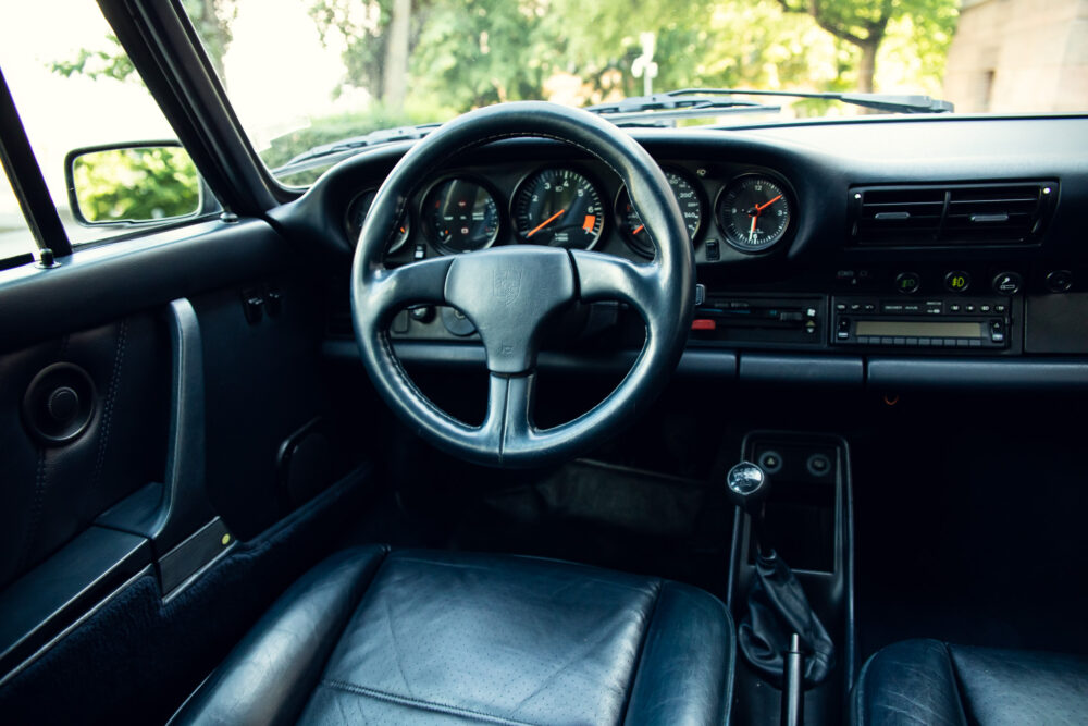 Vintage car interior with steering wheel and dashboard.