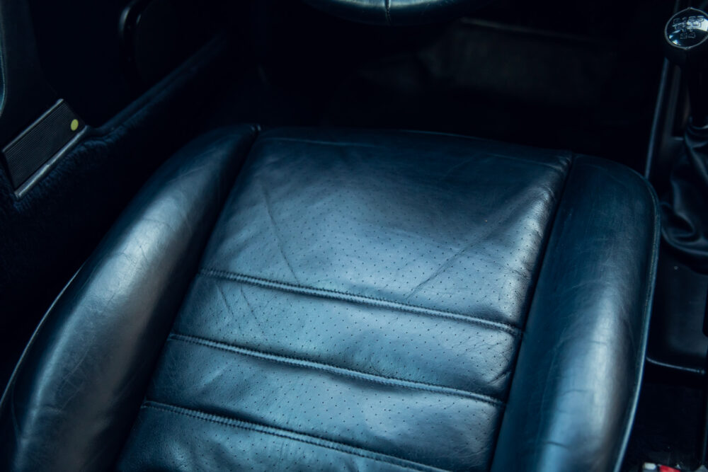 Close-up of a worn black leather car seat