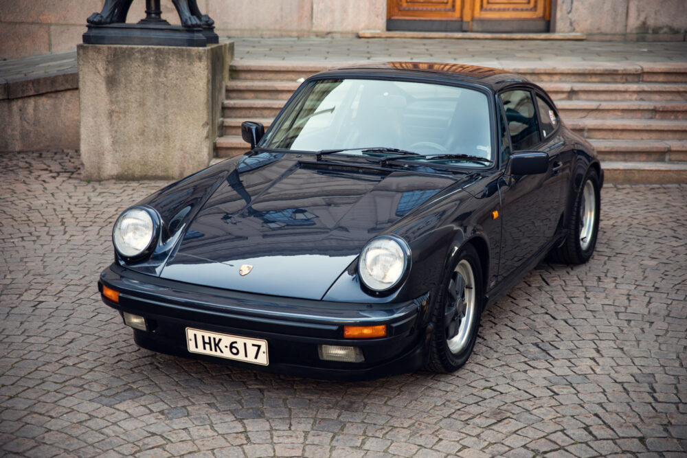 Vintage black Porsche parked by cobblestone steps