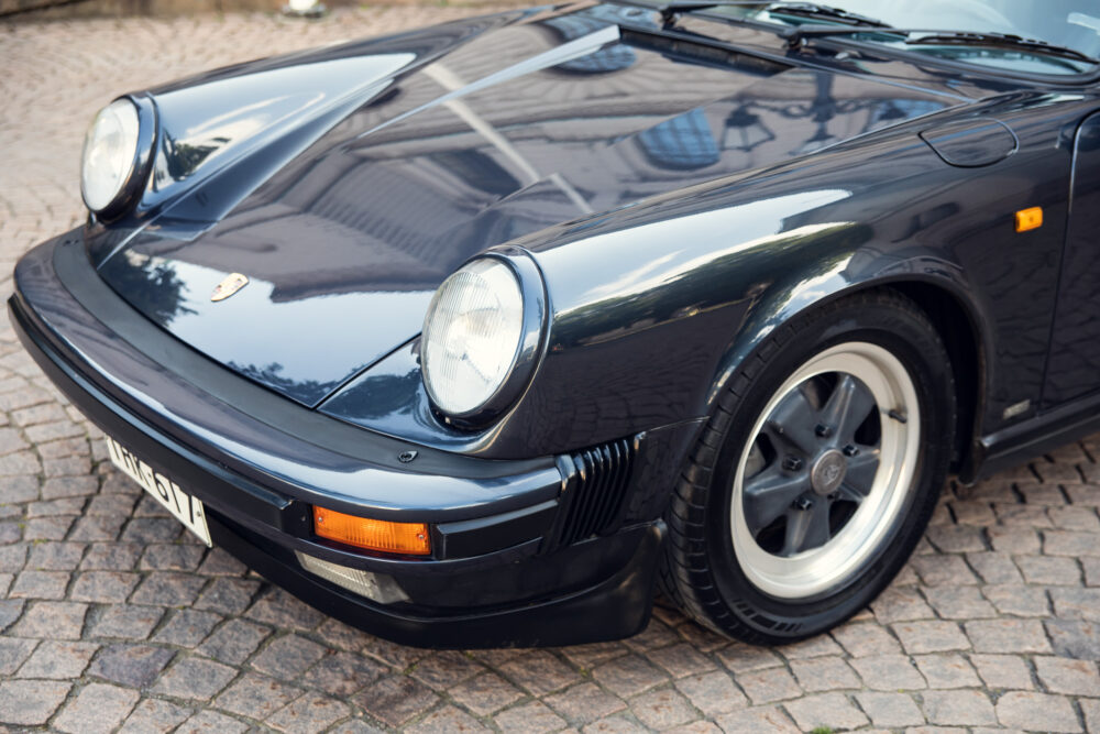 Vintage black Porsche car parked on cobblestone street