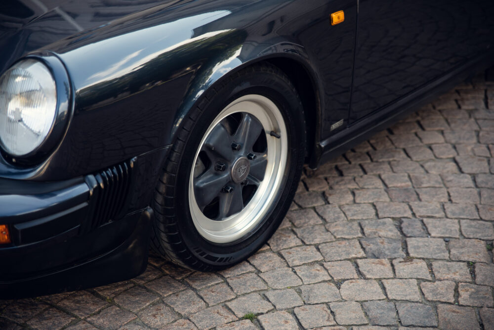 Close-up of vintage car's front and wheel on cobblestone