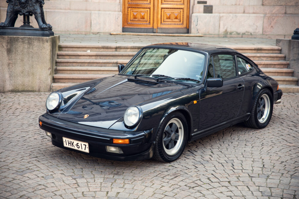 Vintage black Porsche 911 parked by stone steps