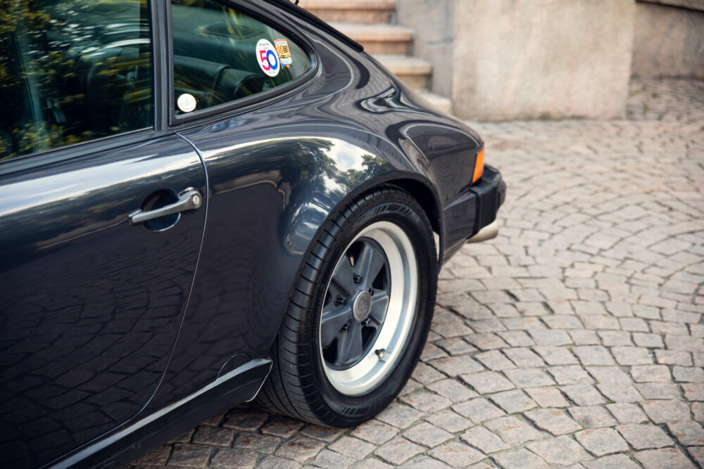 Classic black Porsche with anniversary sticker on cobblestone