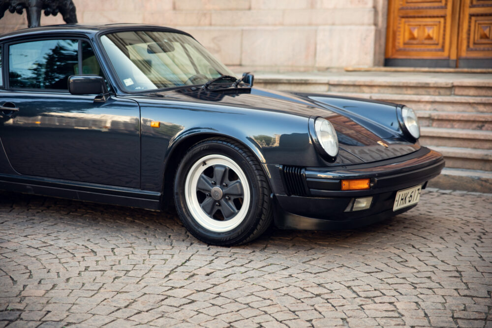 Vintage black Porsche parked near building entrance
