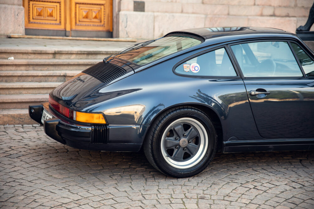 Vintage black Porsche parked by stone steps