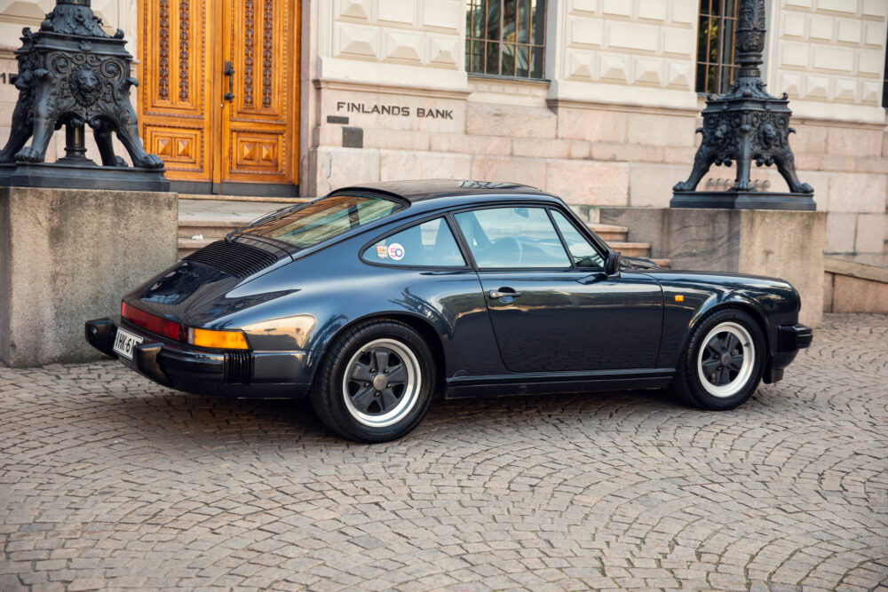Vintage black Porsche parked near ornate building entrance