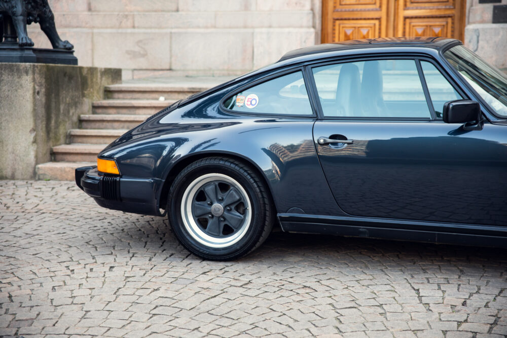 Classic black Porsche car parked beside historic building