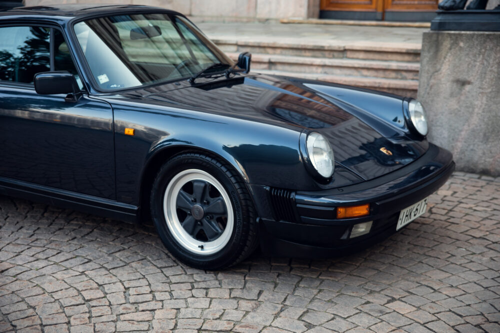 Vintage black Porsche car parked on cobblestone street