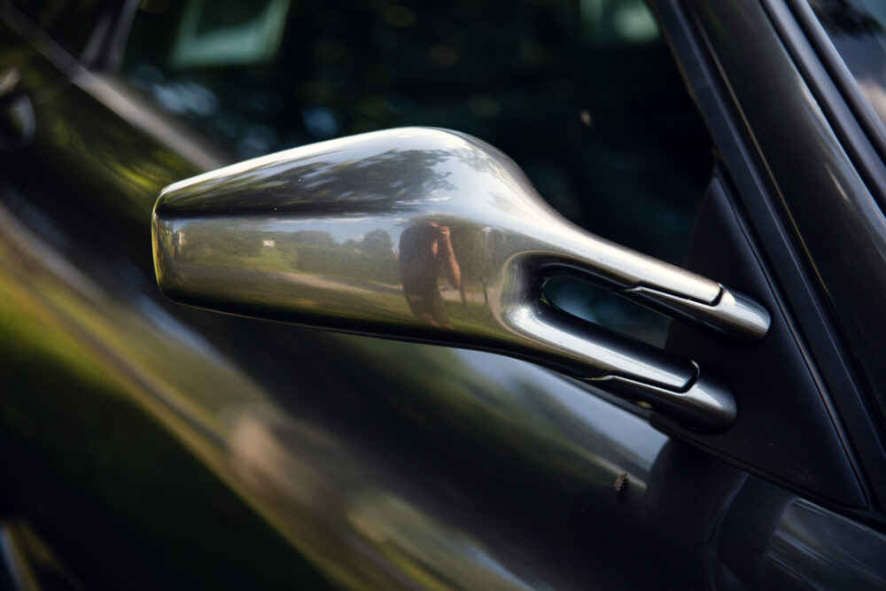 Photographer reflected in shiny car side mirror