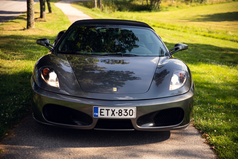 Gray Ferrari parked on sunny tree-lined road