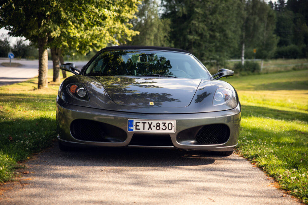 Gray Ferrari parked on tree-lined road.