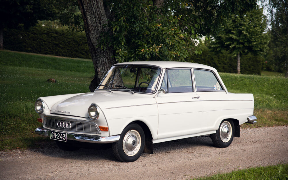 Vintage white Audi parked by tree in lush park