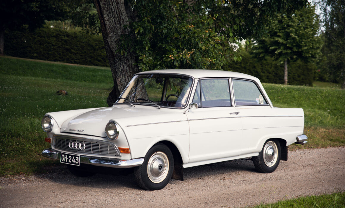 Vintage white Audi parked by tree in lush park