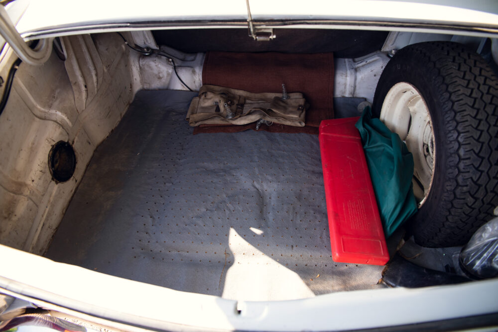Vintage car trunk with spare tire and tools.