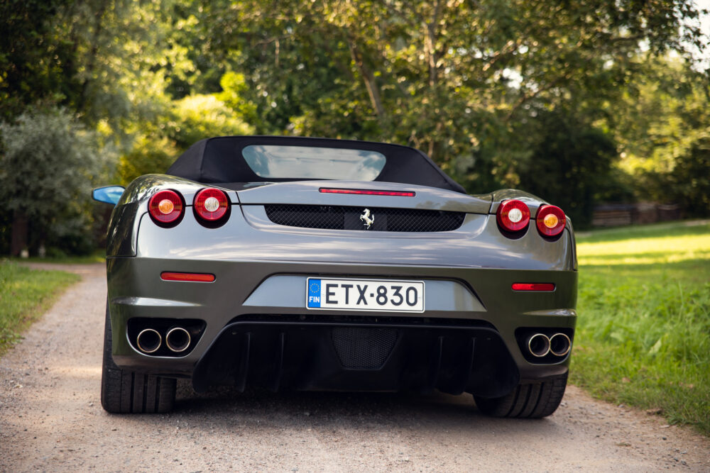 Silver convertible sports car on tree-lined dirt road