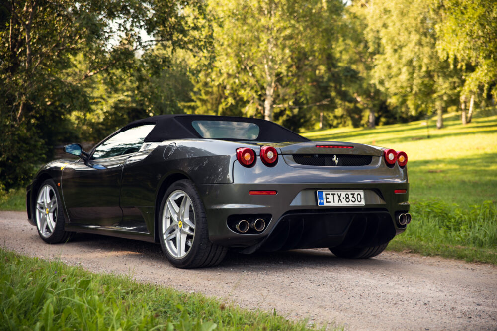 Black Ferrari convertible car on park road