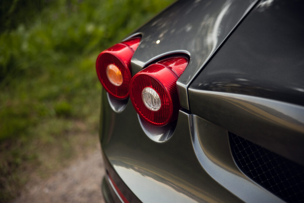 Close-up of red car taillights with green foliage background