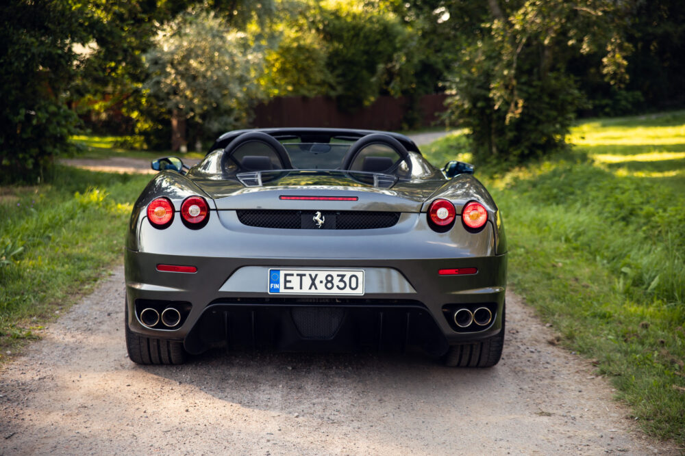 Silver convertible Ferrari on a forest-lined road