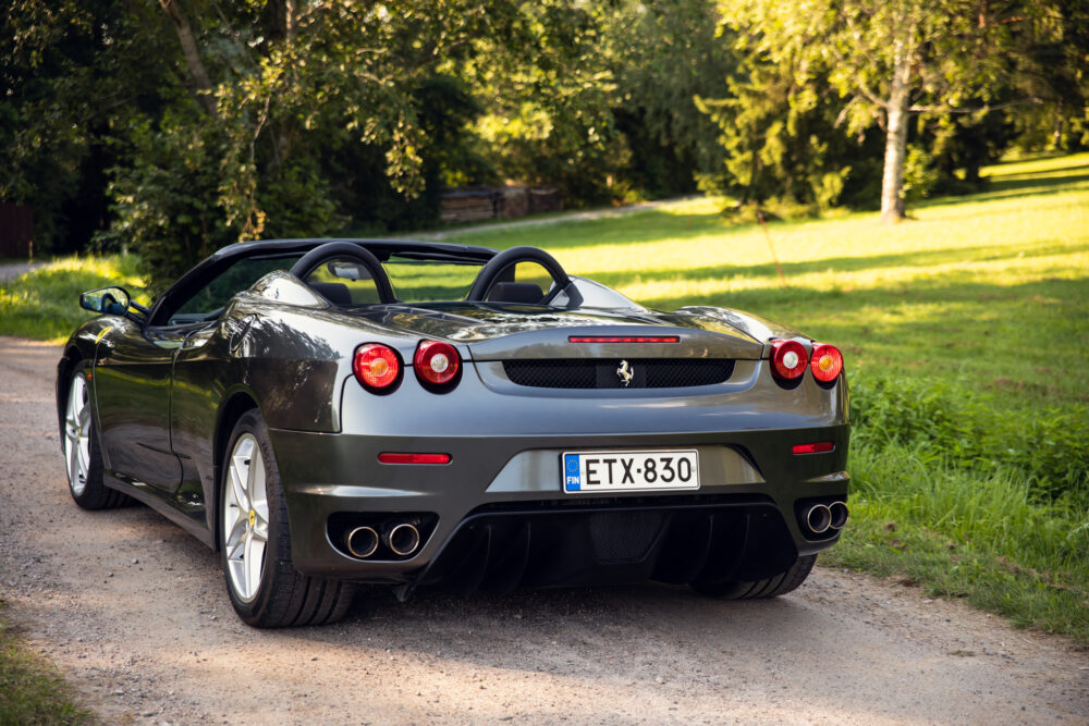 Green Ferrari convertible parked on a rural road
