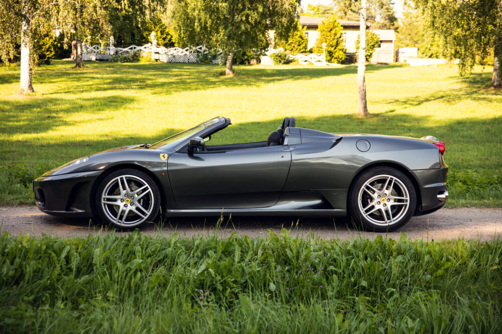 Gray convertible sports car parked beside green grass.