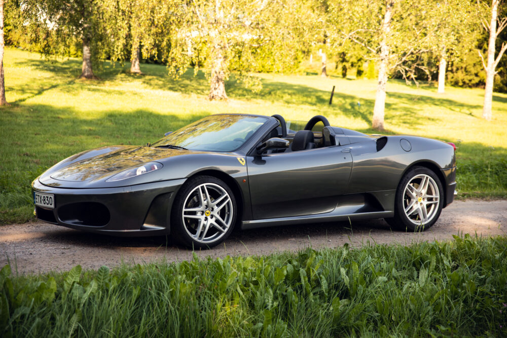 Gray convertible sports car parked in a lush park