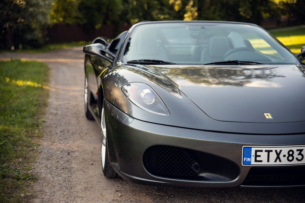 Gray Ferrari parked on a tree-lined country road