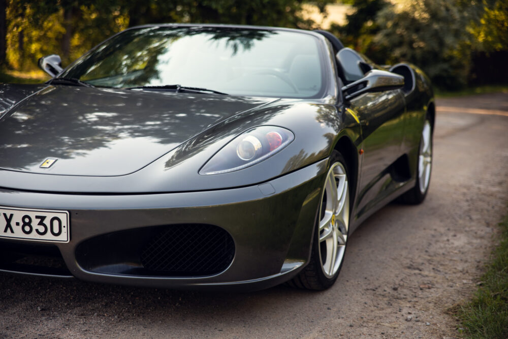 Green Ferrari parked on a tree-lined road