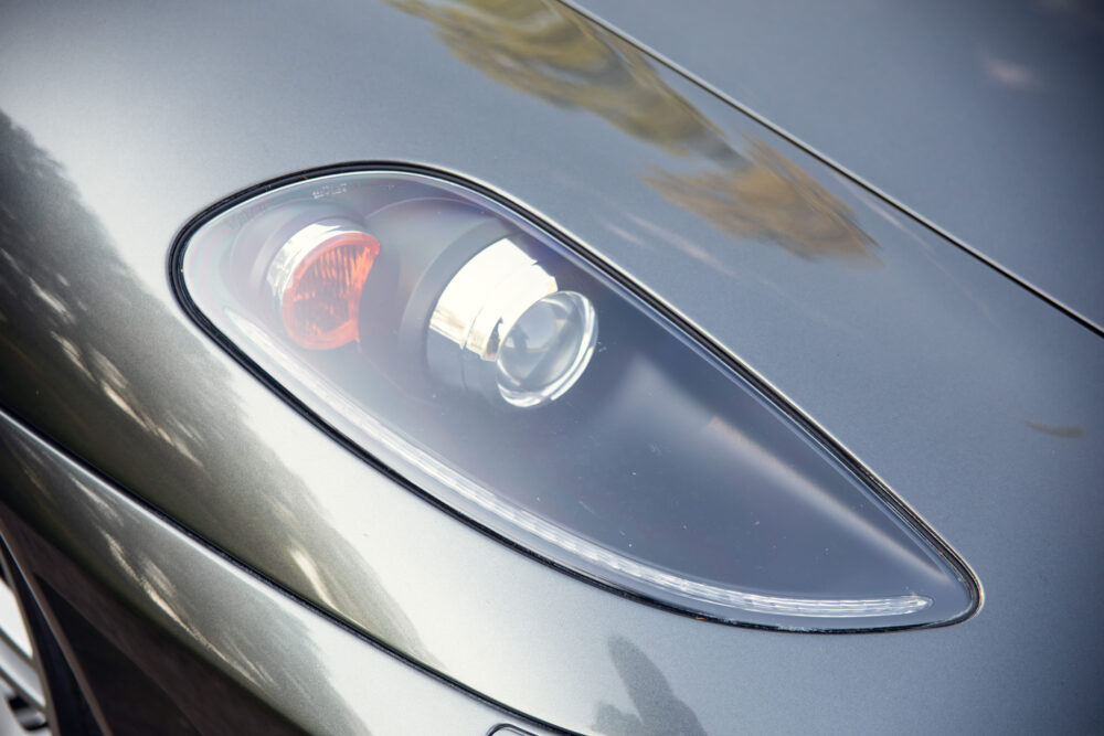 Close-up of modern car headlight on gray hood