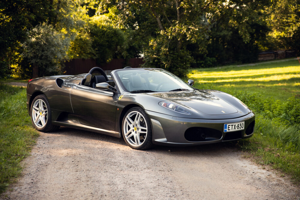 Gray convertible sports car parked beside greenery