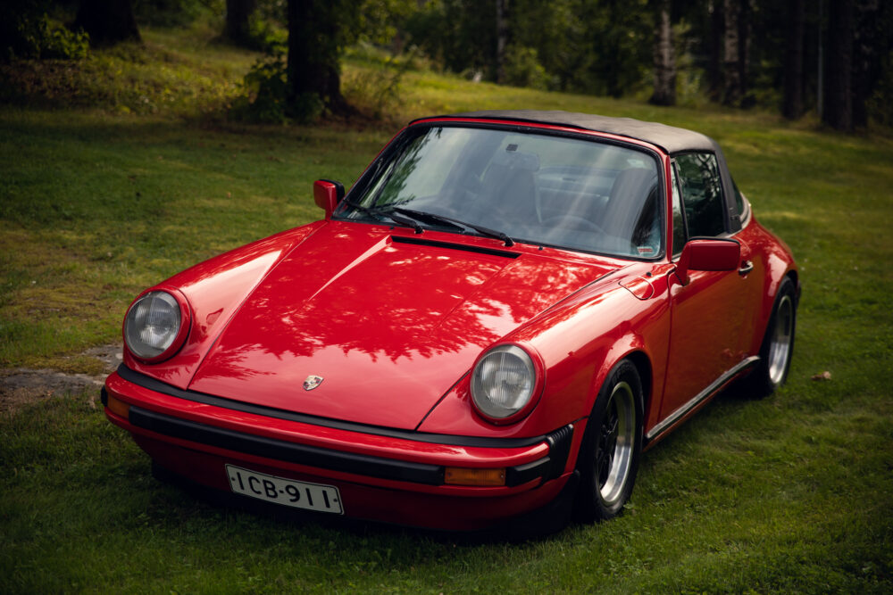 Red vintage Porsche car parked on grassy field