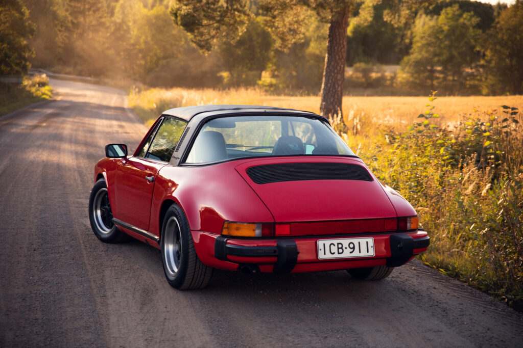 Red vintage Porsche driving on a sunny country road