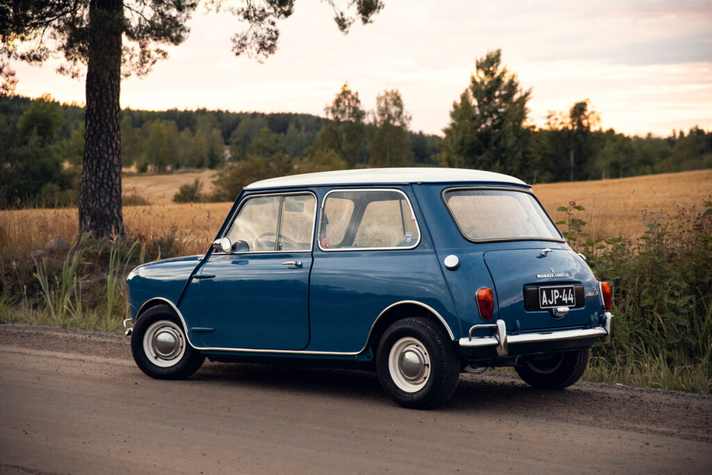 Vintage blue Mini Cooper in rural landscape at dusk