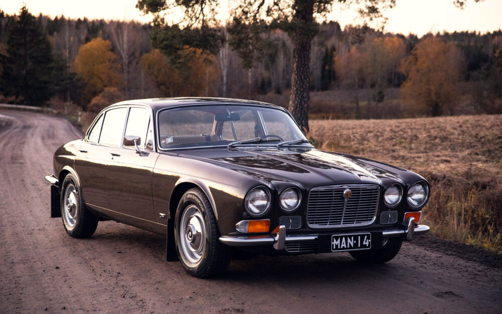Vintage Jaguar car on a scenic forest road at dusk