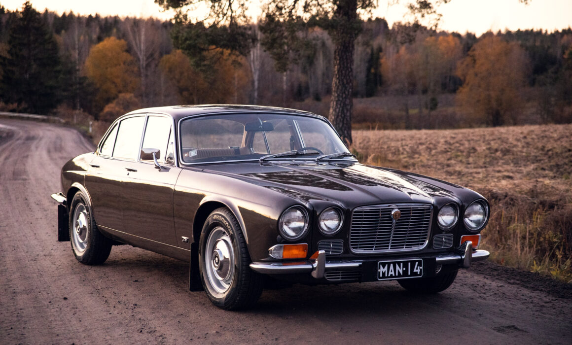 Vintage Jaguar car on a scenic forest road at dusk