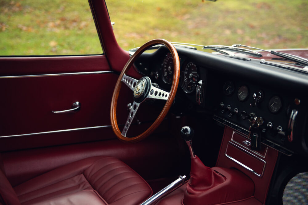 Vintage car interior with red leather and wood steering wheel