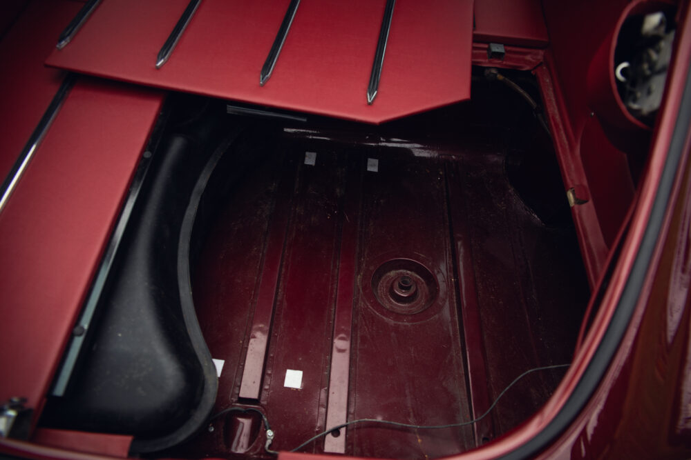 Empty red car trunk with raised front hood