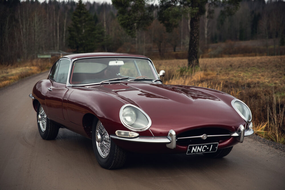 Vintage maroon Jaguar E-Type on rural road