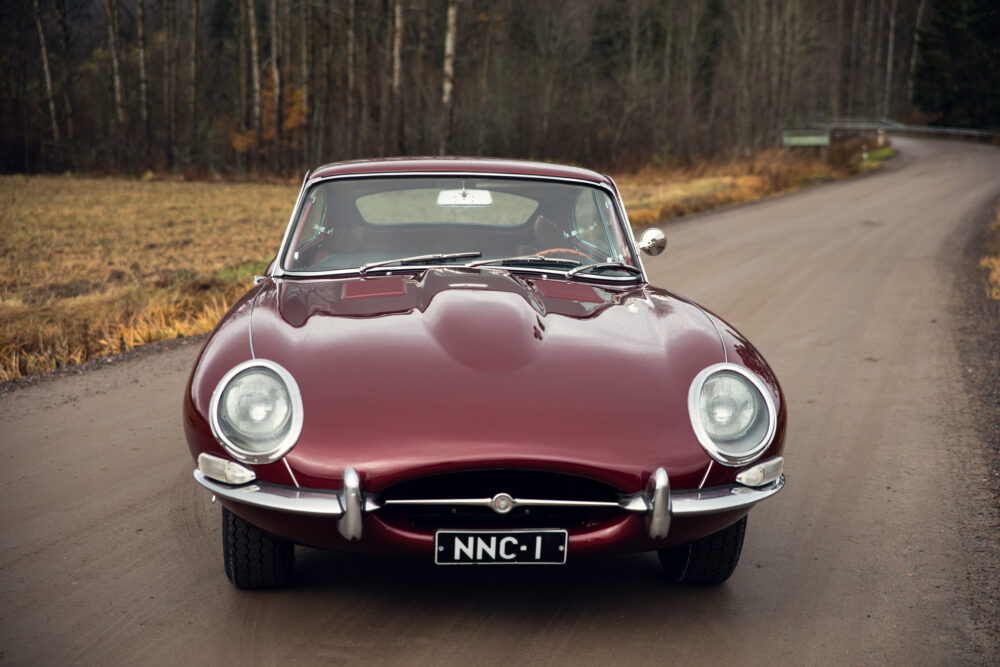 Vintage red Jaguar E-Type on forest roadside