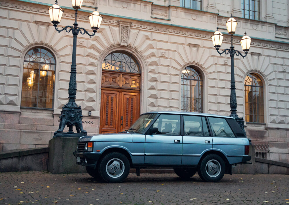 Blue SUV parked outside a historic building at dusk