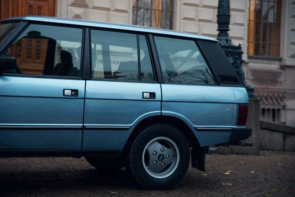 Blue vintage station wagon parked near historic building