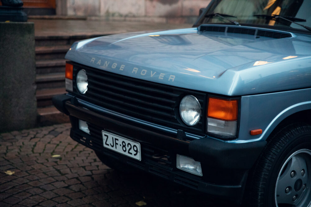 Vintage Range Rover parked on cobblestone street.